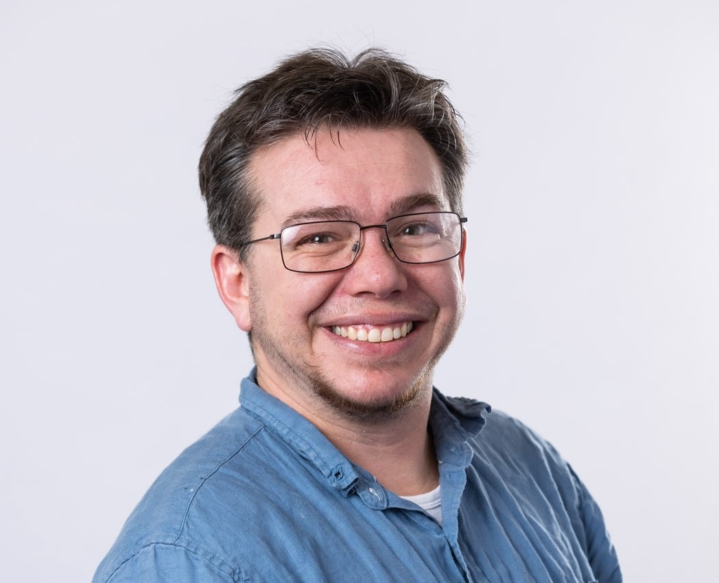 Image of Professor Andy Perfors, wearing a blue shirt and black framed glasses. 