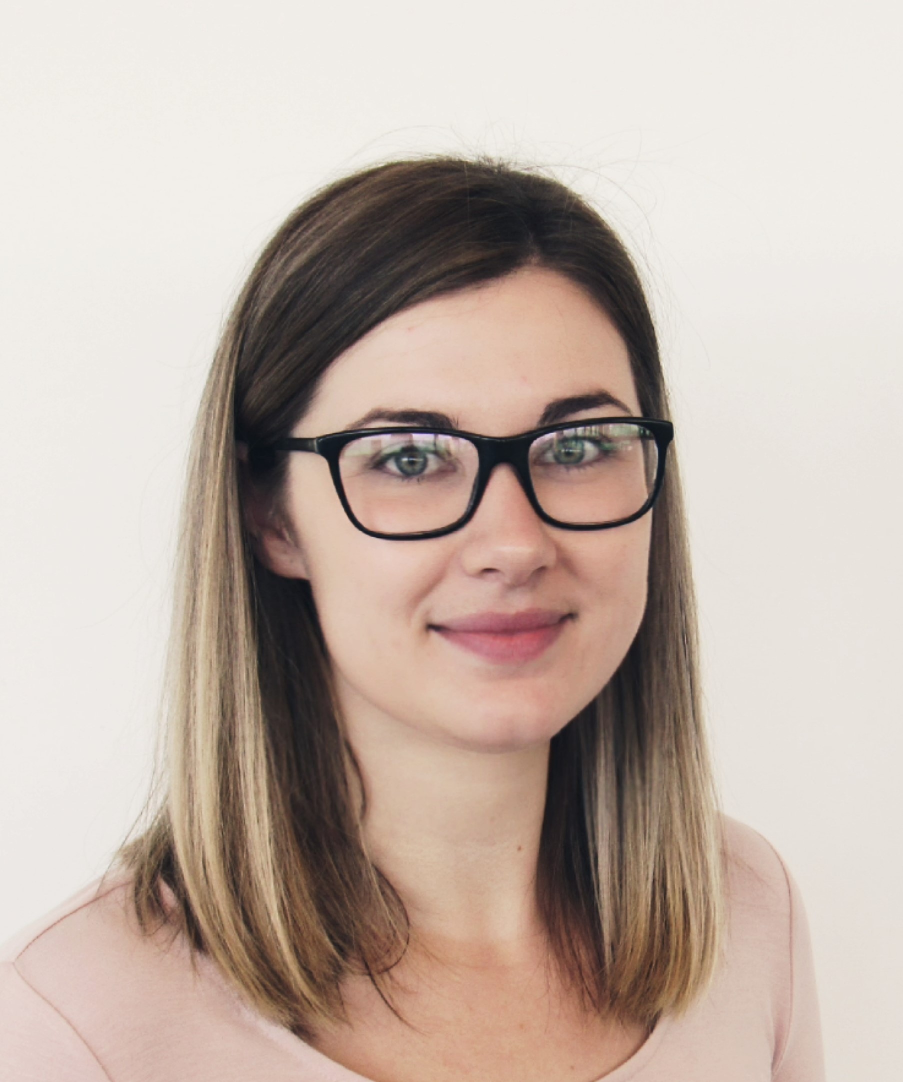 A portrait image of smiling Dr Rachel McQuade with long brown hair and a pair of glasses