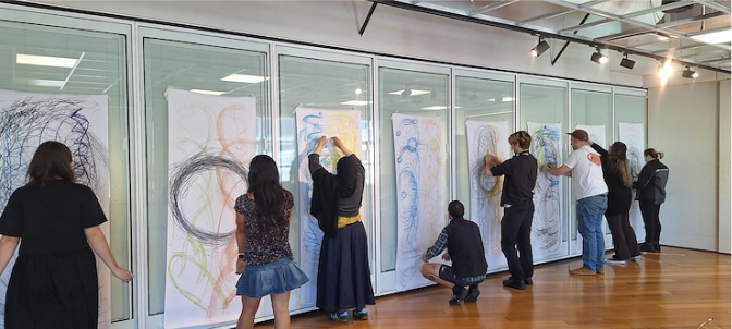 VAD students drawing on big pieces of paper hung up on the walls 