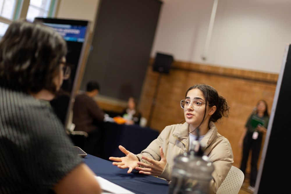 Image of a student speaking to Students@Work staff across a table. 