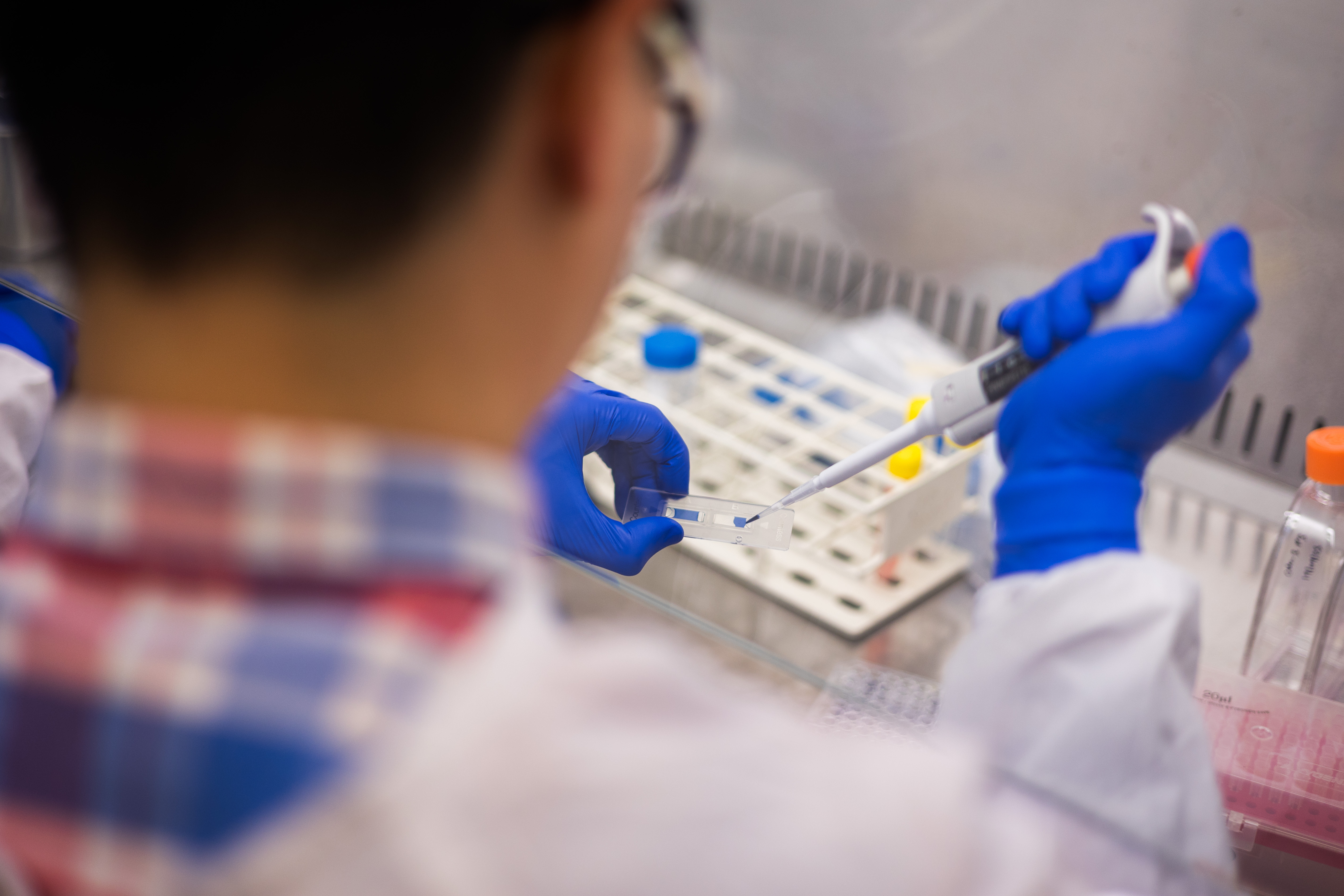 Researcher in clinical lab holding a pipette.