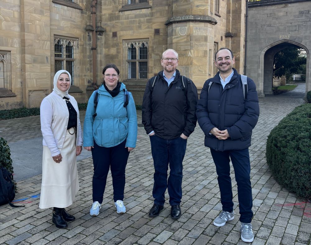 Image of four Kings College Staff Members standing in front of the University of Melbourne clock tower building